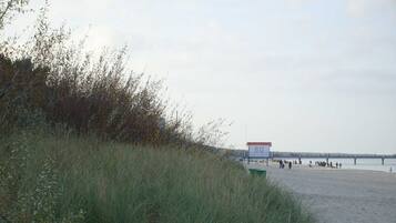 Ein Strand mit einem Schild mit der Aufschrift '8G' und einem Steg im Hintergrund.
