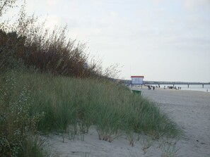 Ein Strand mit einem Schild mit der Aufschrift '8G' und einem Steg im Hintergrund.
