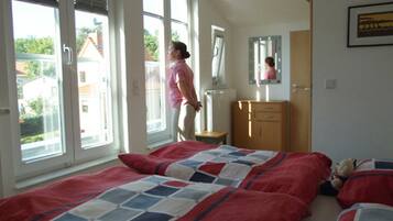 Ein Schlafzimmer mit zwei Betten, einer Holzkommode, einem Spiegel und einem Fenster mit Jalousien.