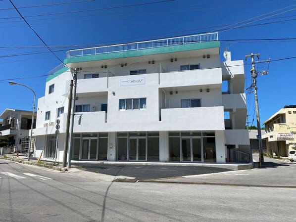 Un edificio de varios pisos con fachada plana, ventanas grandes y techo verde.