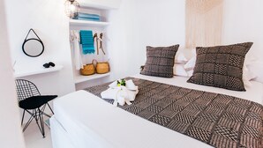 Une chambre moderne avec un lit, une chaise, une étagère avec des serviettes et un luminaire suspendu.