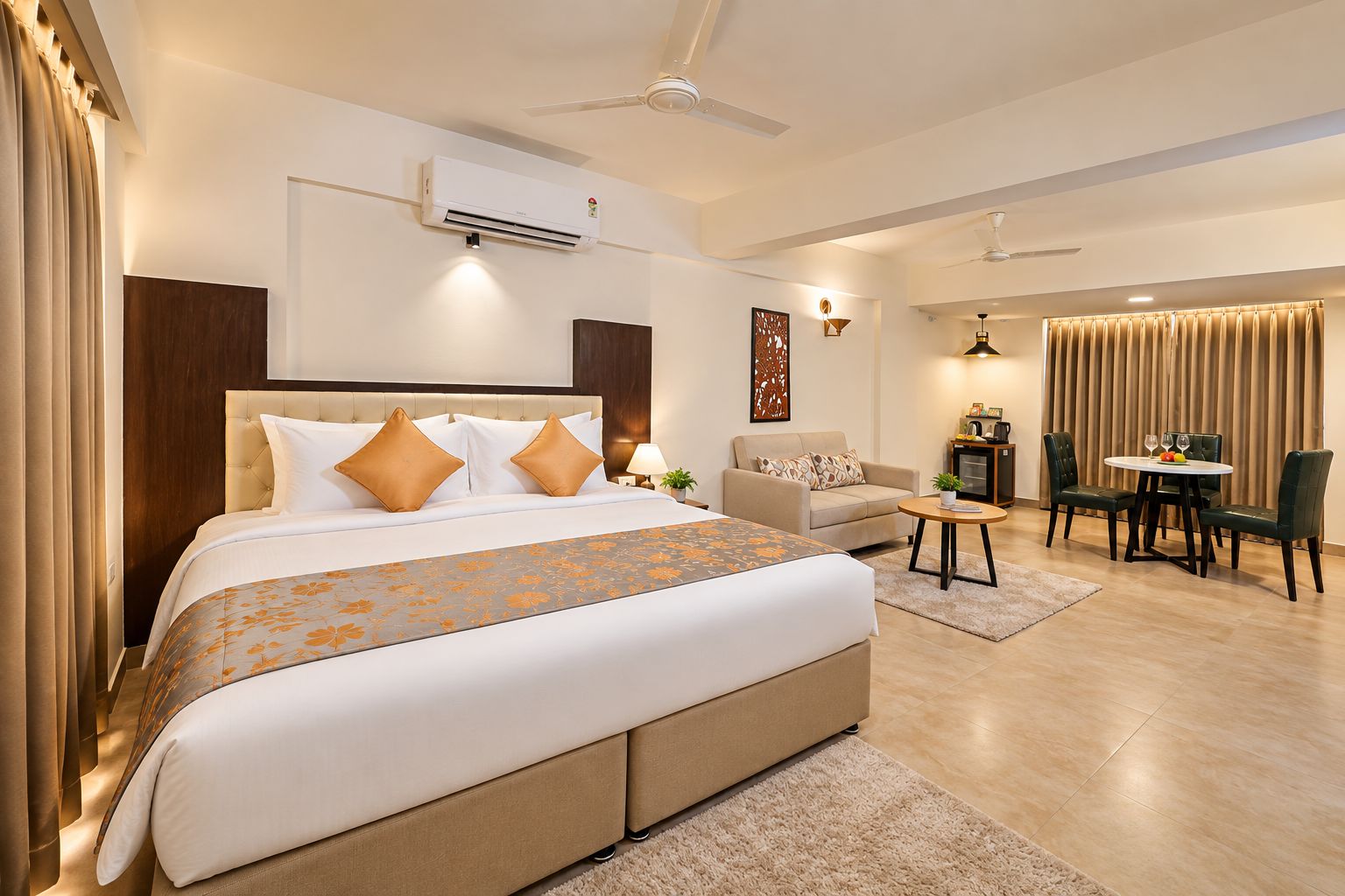 Une chambre d’hôtel dotée d’un grand lit, d’un canapé, d’une table à manger avec des chaises, d’un climatiseur et d’un ventilateur de plafond.