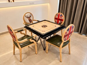 A square table with a shuffleboard game setup, surrounded by four chairs with British flags. - The Altruist Whitefield Hotel (Bengaluru)
