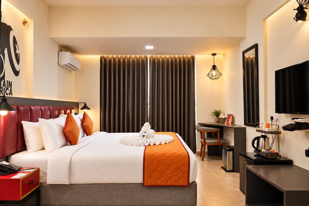 A hotel room with a large bed, a desk, a television, and a minibar.