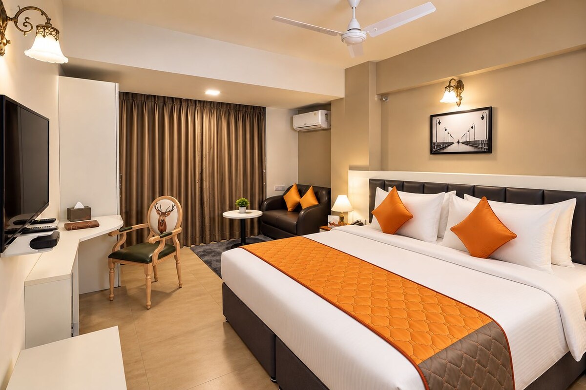 A hotel room with a bed, a desk, a chair, a television, and a ceiling fan.