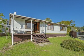 Enjoy a peaceful stay in this cozy home with a front porch and small deck, surrounded by a well-maintained lawn and a wooden fence.