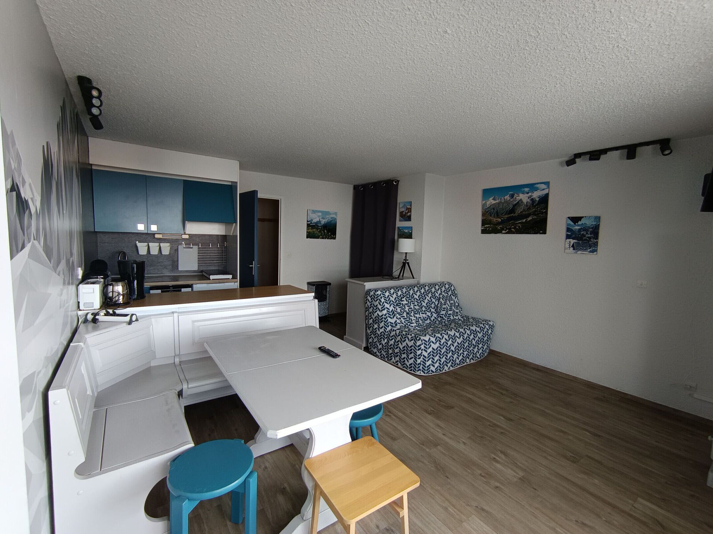 A compact living space with a kitchenette, a dining area with a table and chairs, and a sofa.