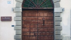 Una gran puerta de madera con un arco de piedra y un ventanal de vidrio verde encima. Se observa un letrero que dice "La Renée" a la izquierda.