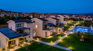 Un moderno complejo residencial con varias casas de dos pisos, una piscina y paneles solares.