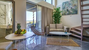 A modern living room with a glass table, a sofa, a chair, and a staircase. - Miroes Suites (Sithonia)