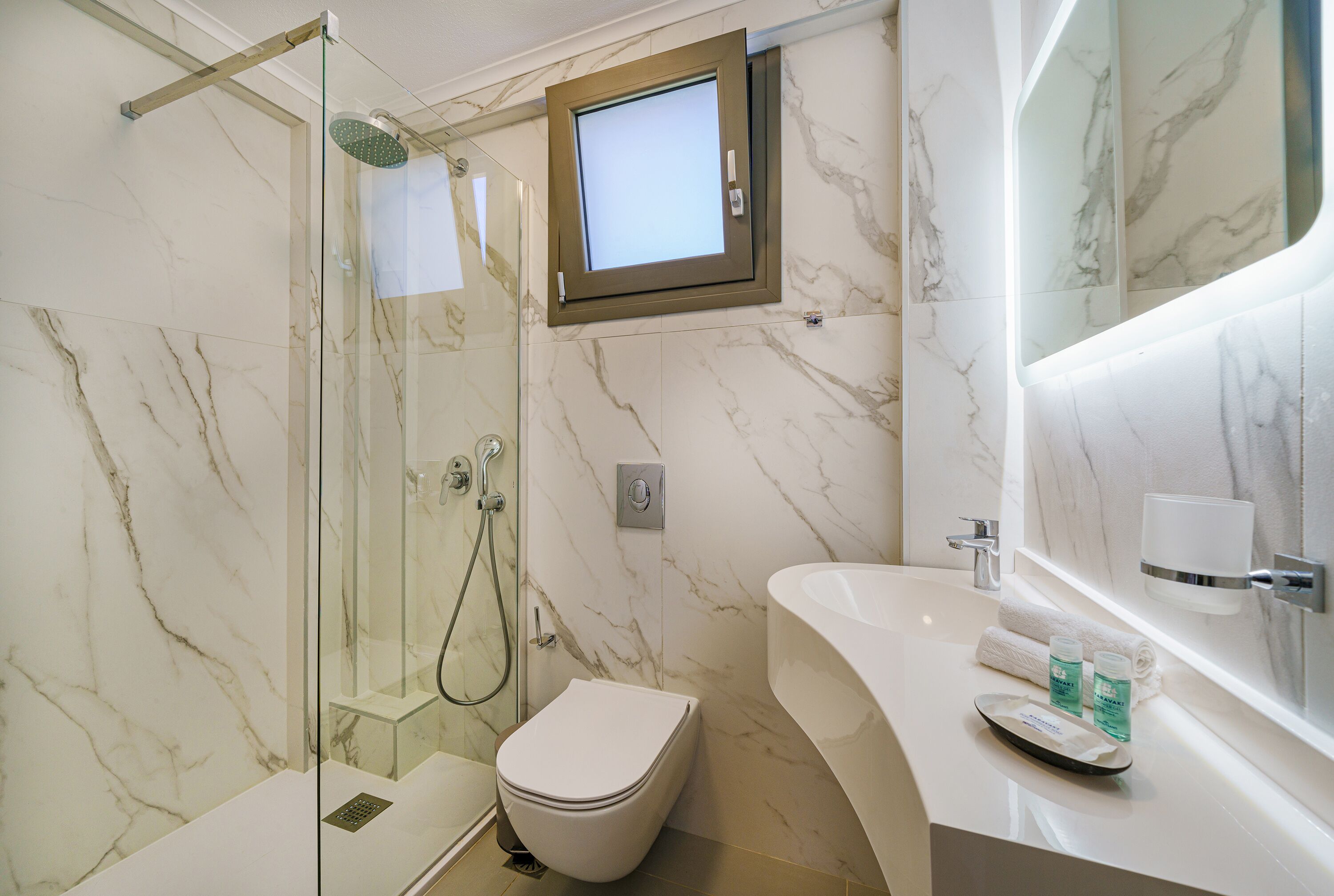 Un baño con ducha de vidrio, inodoro, lavabo y espejo.