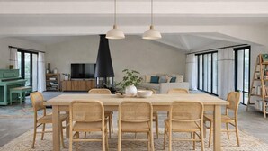 A spacious dining area with a large table and six chairs, a black pendant light, and a potted plant. - Spacious house with pool and beach access (Les Portes-en-Ré)