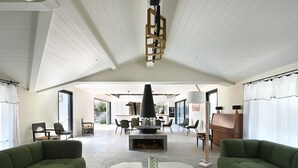 A spacious living room with a high ceiling, a fireplace, and a dining area in the background. - Spacious house with pool and beach access (Les Portes-en-Ré)