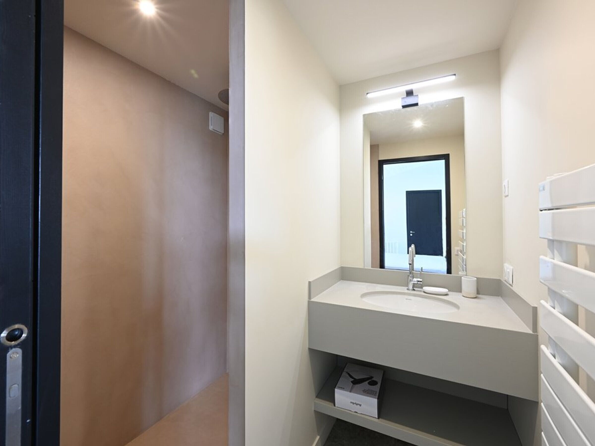 Une salle de bain moderne avec un lavabo blanc, un miroir et une étagère en dessous.