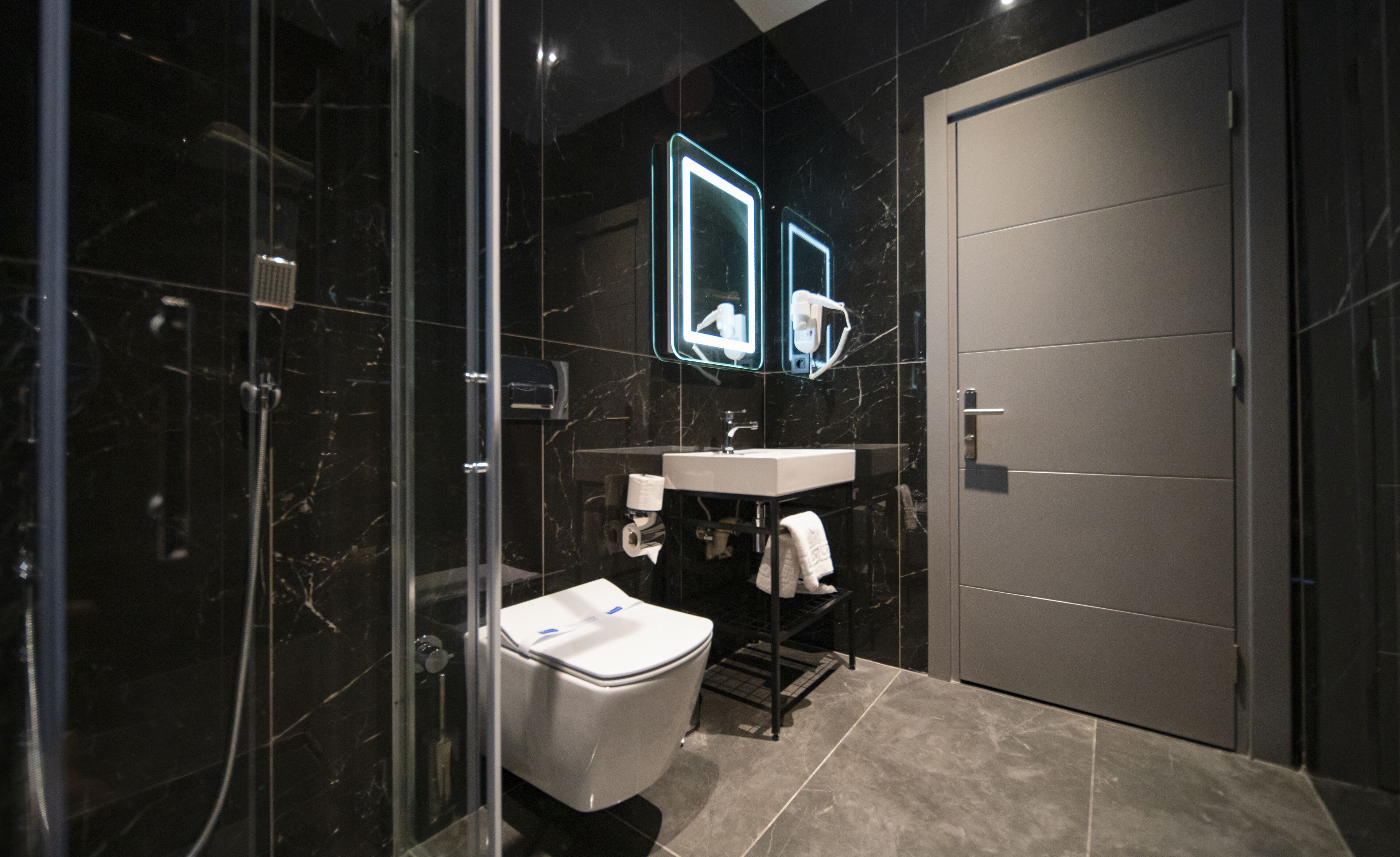 Un baño moderno con ducha acristalada, lavabo blanco y retrete.