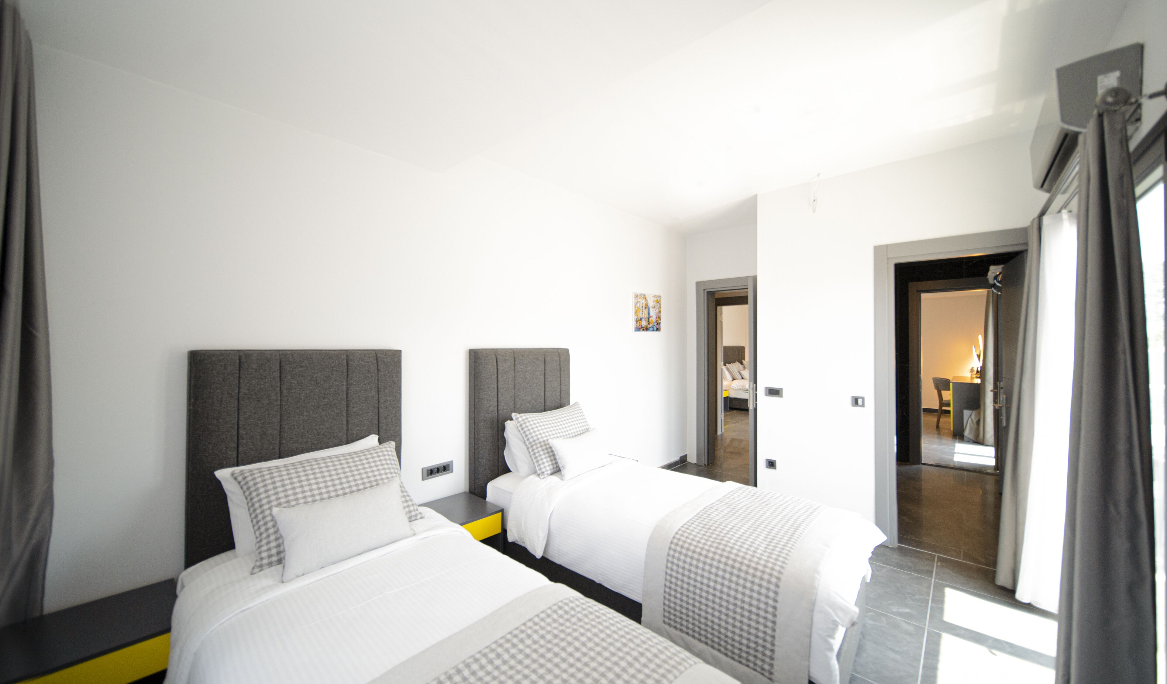 Een hotelkamer met twee bedden, een klein bureau, een stoel en een deur naar een badkamer.
