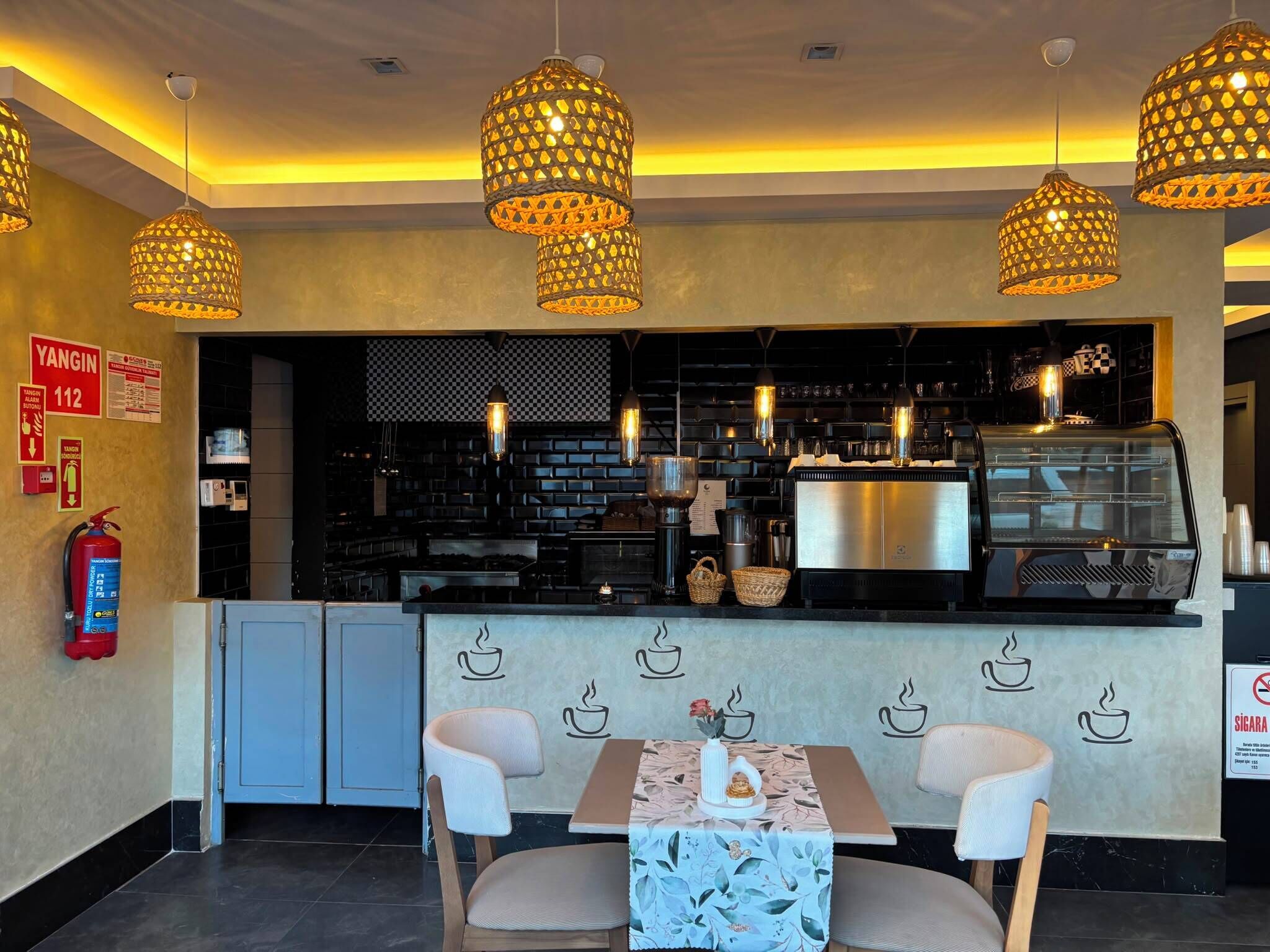 A restaurant with a counter, chairs, and hanging lights.