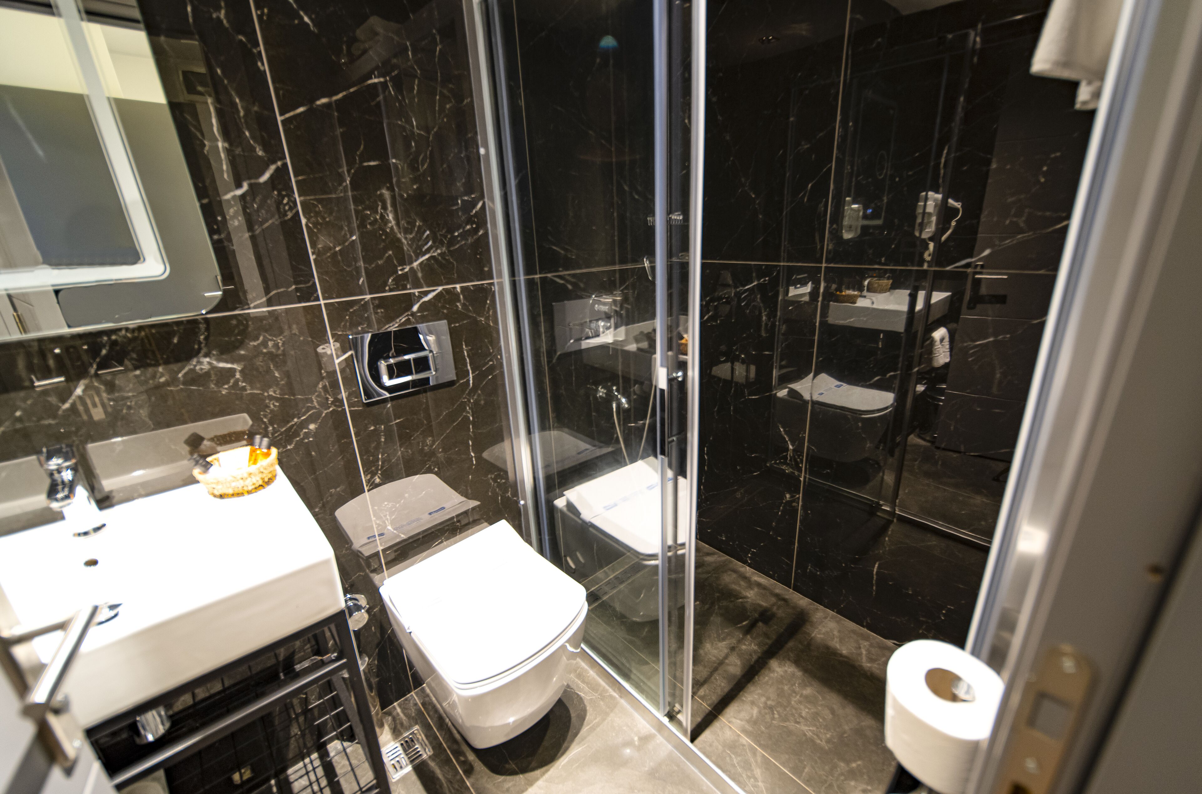 A modern bathroom with a glass-enclosed shower, a toilet, and a sink with a mirror.