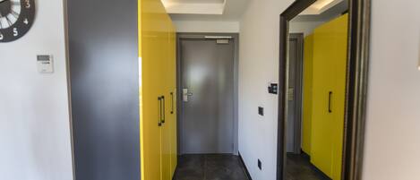 A hallway with a door, a clock, and a mirror.