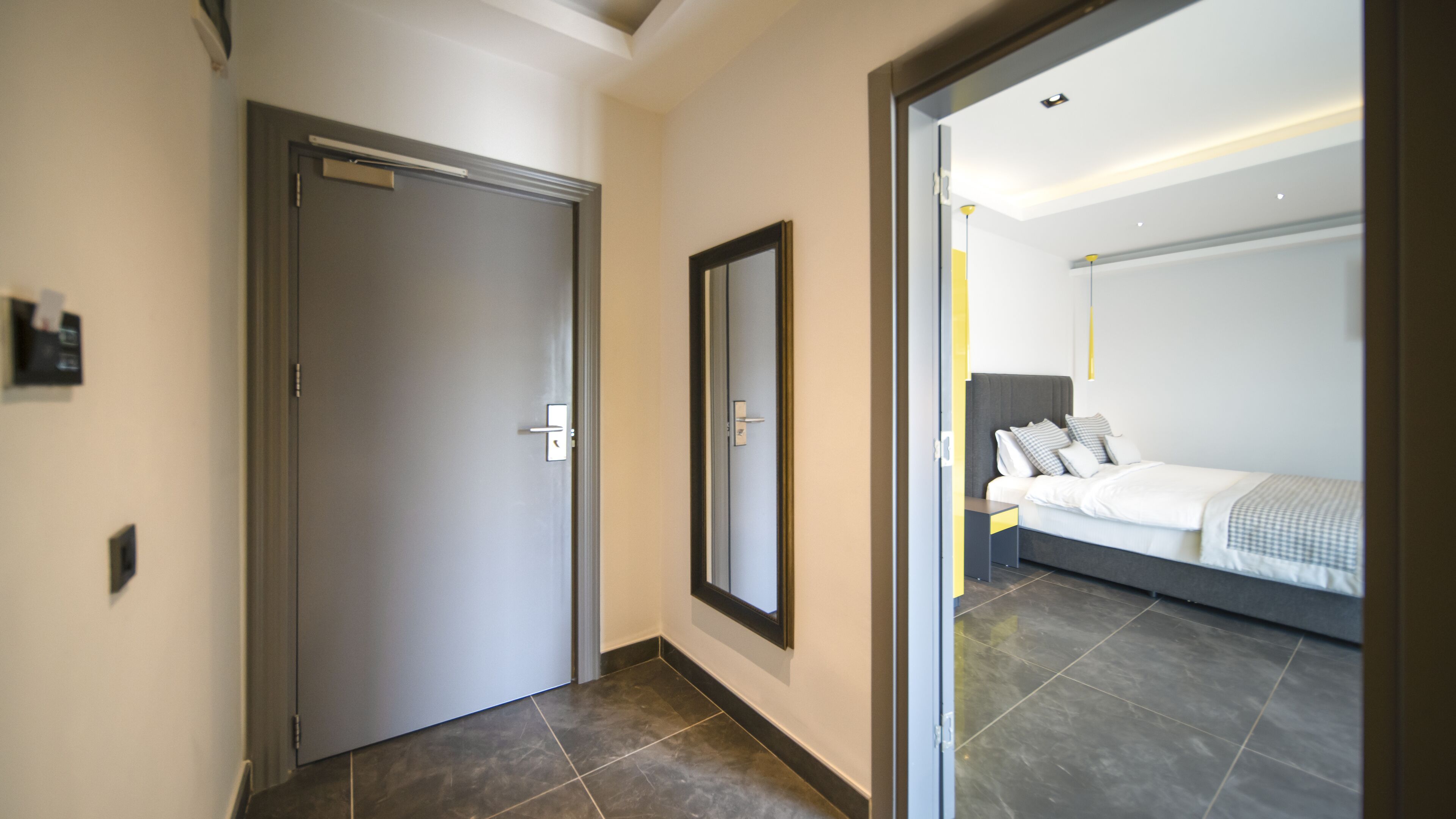 A modern hotel room with a large bed, a bedside table, and a mirror.