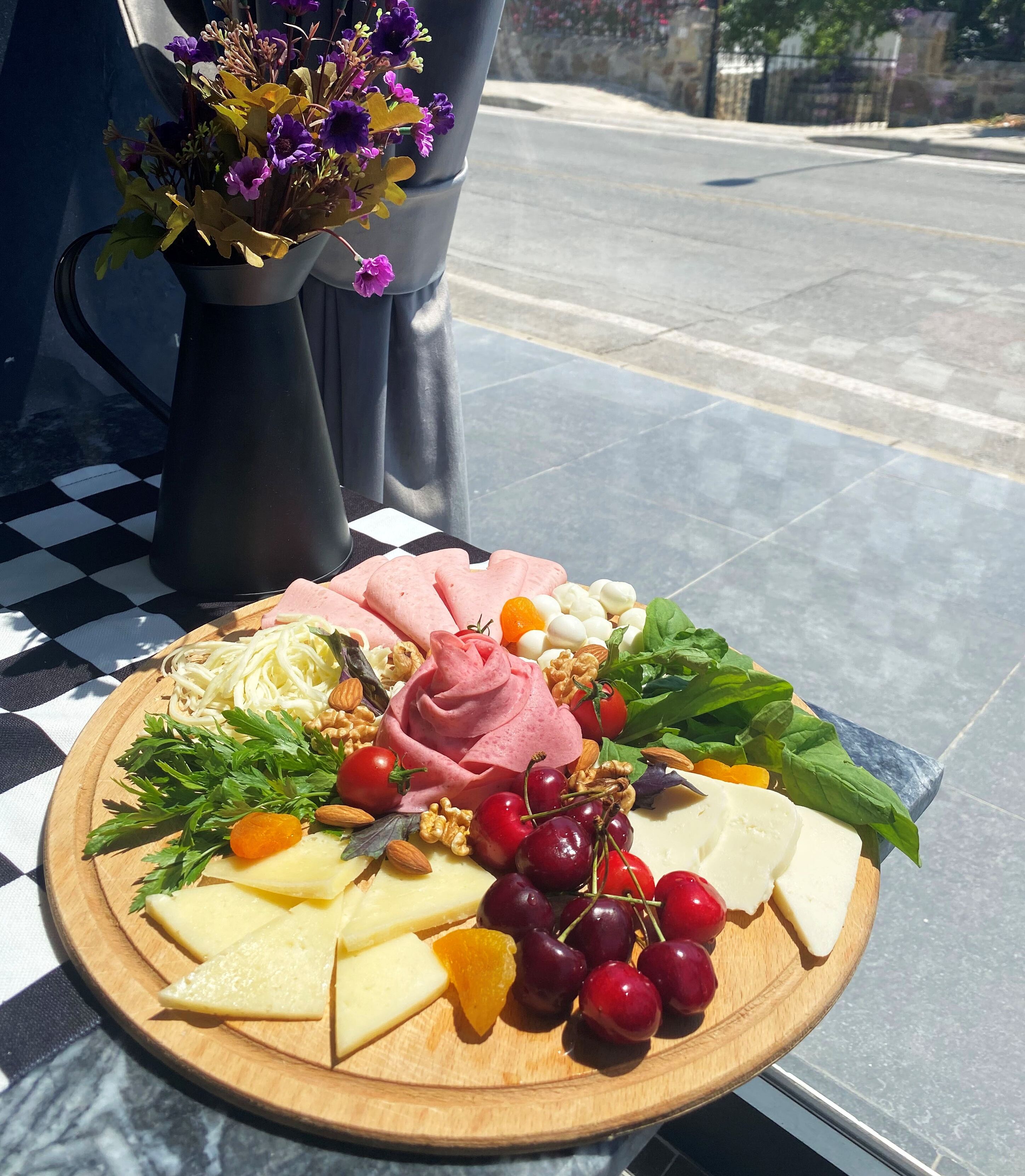 A charcuterie board with various cheeses, fruits, and nuts on a wooden board.