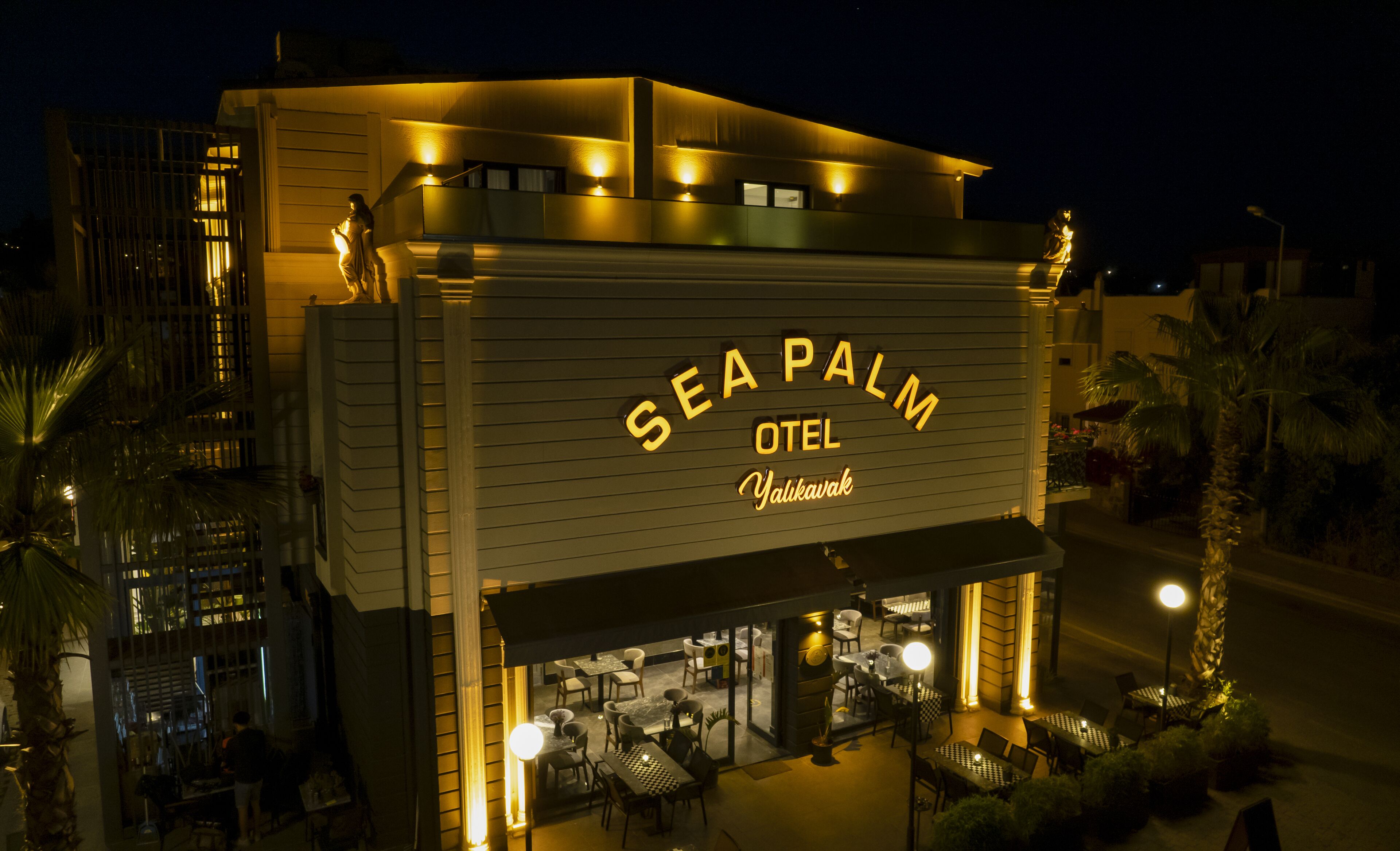 Exterior del hotel Sea Palm, con un letrero destacado, zona de estar al aire libre y palmeras.