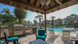 An outdoor patio with a barbecue area, lounge chairs, and a pool. - 🦩Book Me Baby! Destin Delight in The Villages of Crystal Lakes🦩 (Destin)