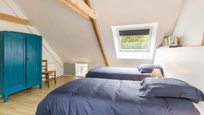 Una camera da letto con due letti, una finestra, un armadio blu e un trave in legno al soffitto.