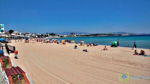 Una spiaggia con persone che prendono il sole e nuotano.