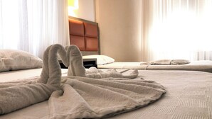 Una camera d'albergo con un letto rifatto, una testiera e una lampada.