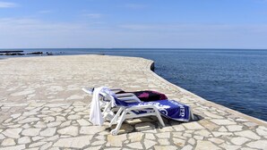 Ein Strandbereich mit Kiespflaster, Liegestühlen und einem Pool.