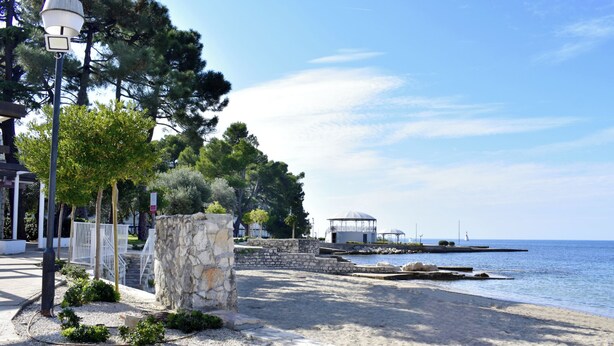 Eine Küstenpromenade mit Steinwegen, einem Gazebo und Blick auf das Meer.