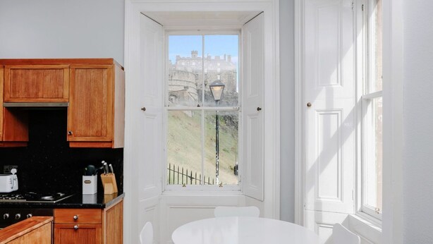 A kitchen with wooden cabinets, a stove, and a window with a view of a castle.