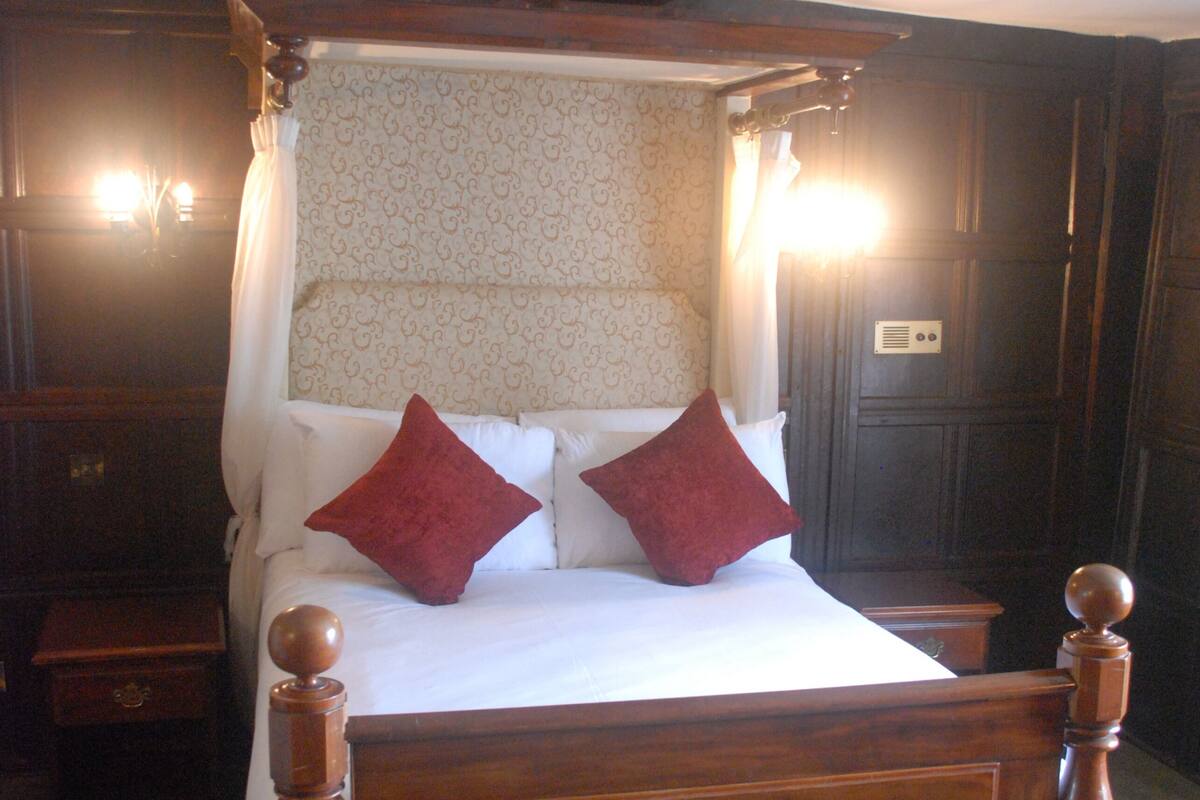 A four-poster canopy bed with a wooden frame and a headboard with a patterned design.