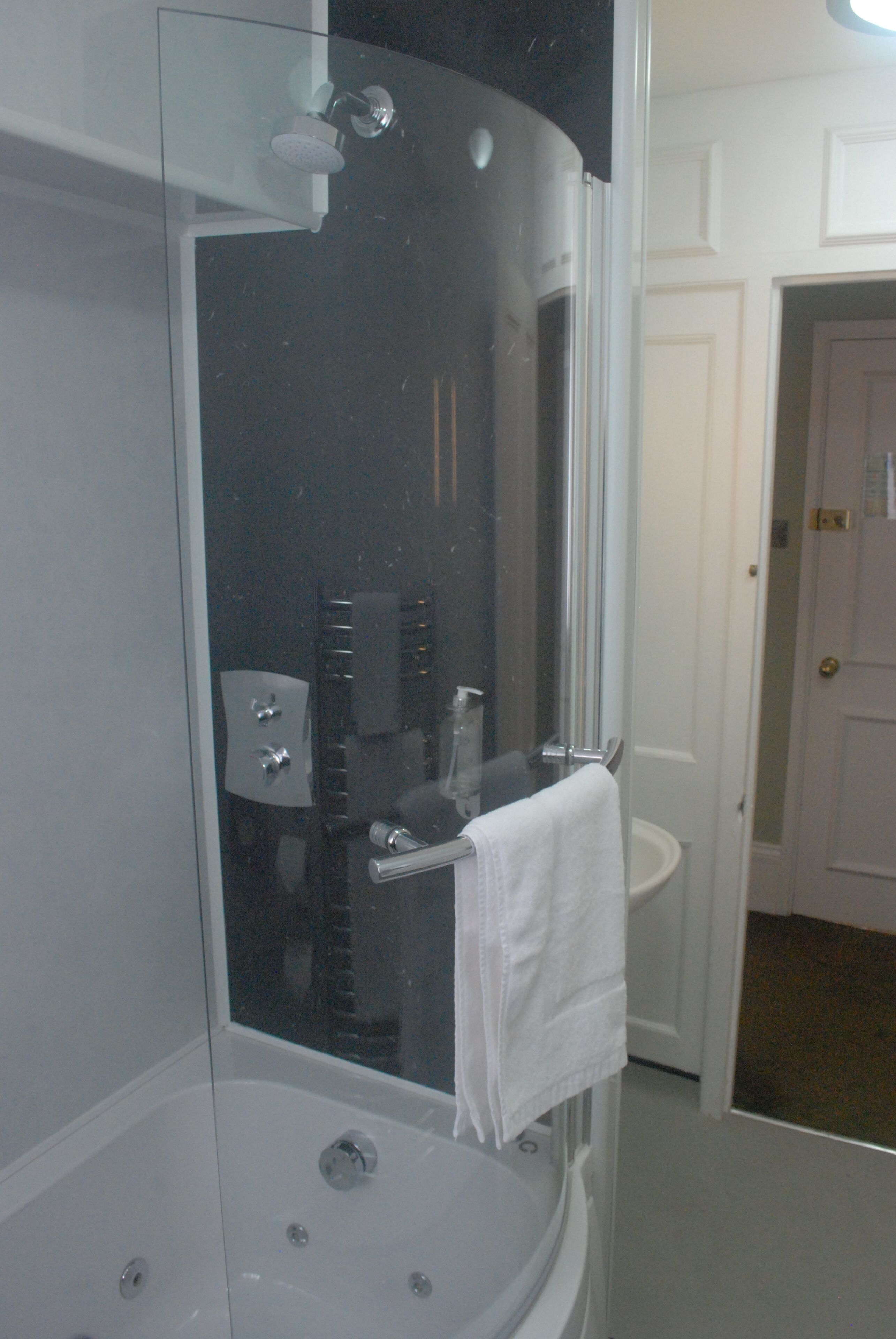 A modern bathroom with a glass-enclosed shower, a white sink, and a towel hanging on a rack.