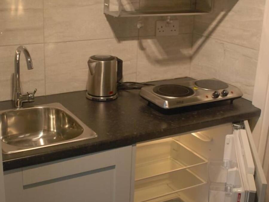 A compact kitchen with a sink, a kettle, a microwave, and a built-in oven.