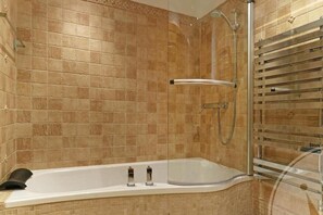 Un baño moderno con una bañera independiente, ducha con mampara de vidrio y un perchero para toallas.