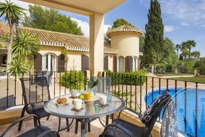 Un patio con una mesa redonda, sillas y una piscina.
