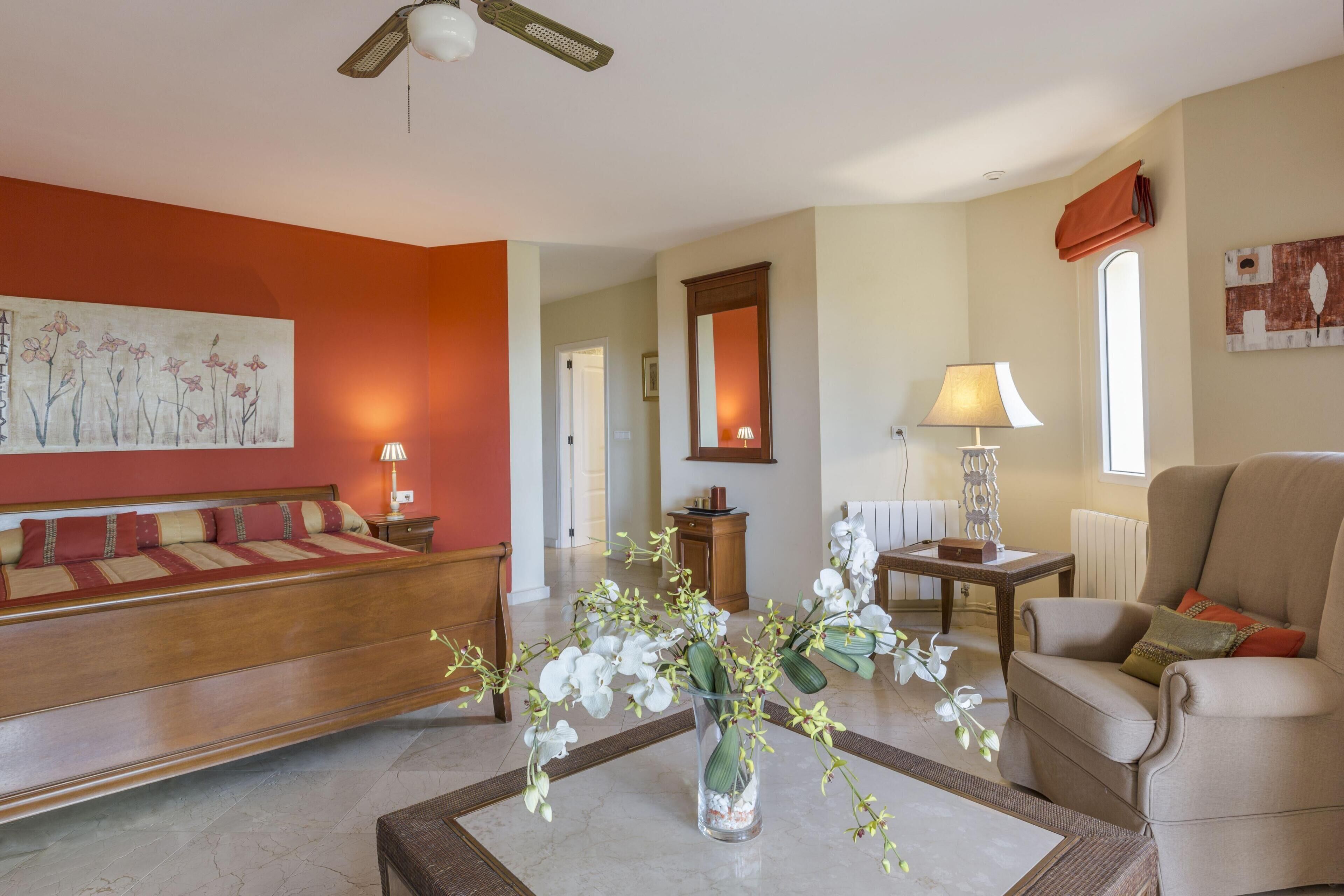 A spacious living room with a sofa, armchair, and a coffee table with a vase of flowers.
