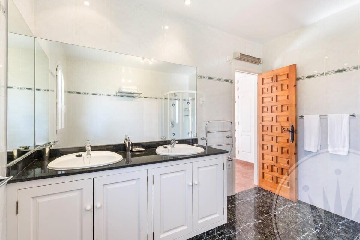 Une salle de bain moderne avec deux lavabos, un grand miroir et une douche.