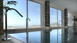Une piscine intérieure offrant une vue dégagée sur le paysage, un robinet moderne et un sol carrelé.