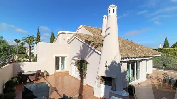 Una casa moderna con un patio, una chimenea y vistas del paisaje circundante.