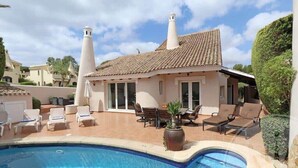 Una villa con piscina, mobiliario de exterior y jardín.