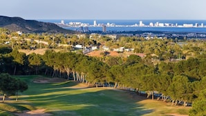 Campo de golf con el horizonte de una ciudad al fondo.