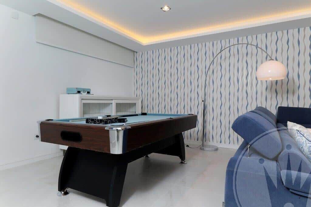 A modern room with a pool table, a sofa, and a patterned wall.