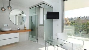 A modern bathroom with a glass shower enclosure, a round mirror, a white sink, and a glass table. - La Manga Club Las Dalias Villa 564 (La Manga Club, Cartagena)