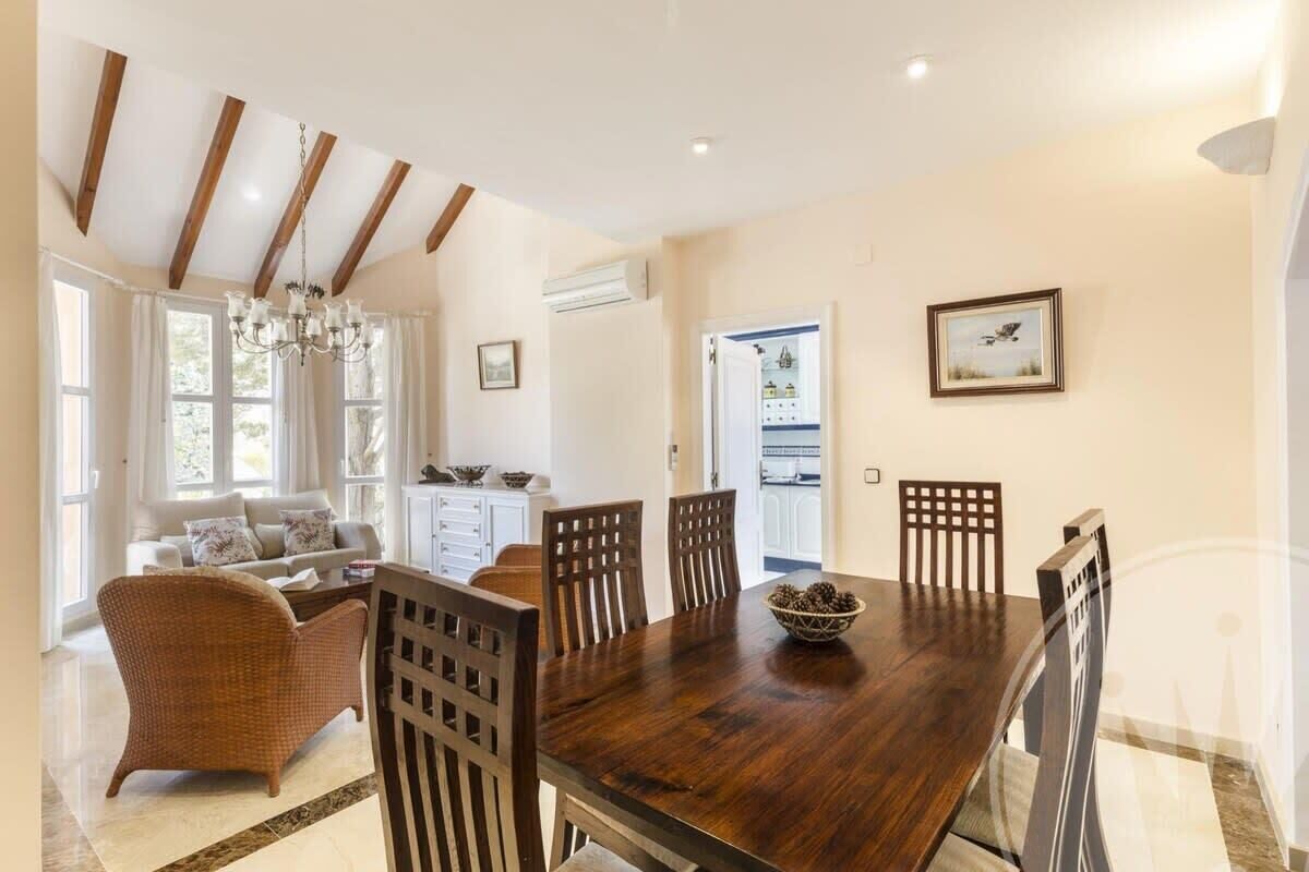 A dining area with a wooden table, six chairs, and a chandelier.