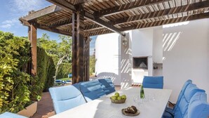 An outdoor patio with a white table, blue cushioned chairs, and a pergola overhead. - La Manga Club Las Brisas Villa 514 (La Manga Club, Cartagena)