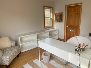 A room with a white desk, a chair, a small window, a door, and a wall-mounted shelf. - Exclusive walk to the beach Lazy Point House (Amagansett)