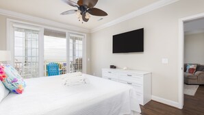 Una camera da letto con un letto, una ventola a soffitto, una TV e una finestra con tende.